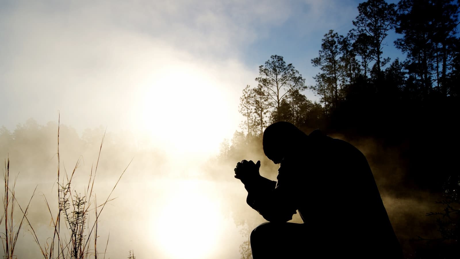 Faith and focus — the silhouette of a man kneeling in prayer